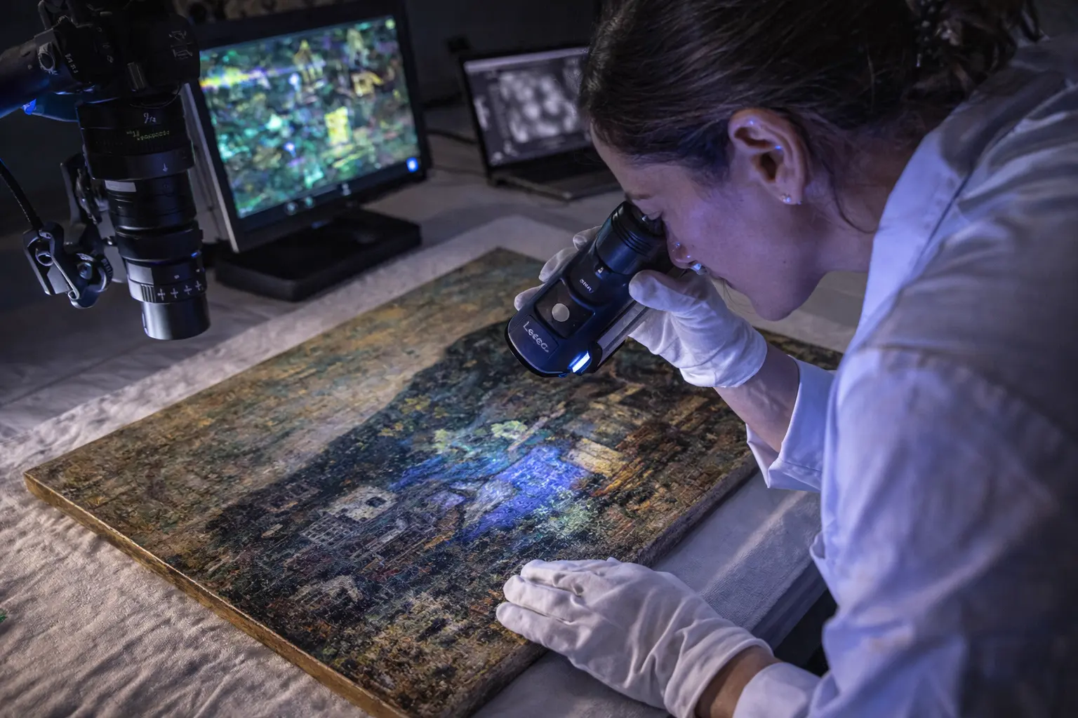 Art conservator examining painting condition assessment diagnostic imaging UV light magnification professional treatment