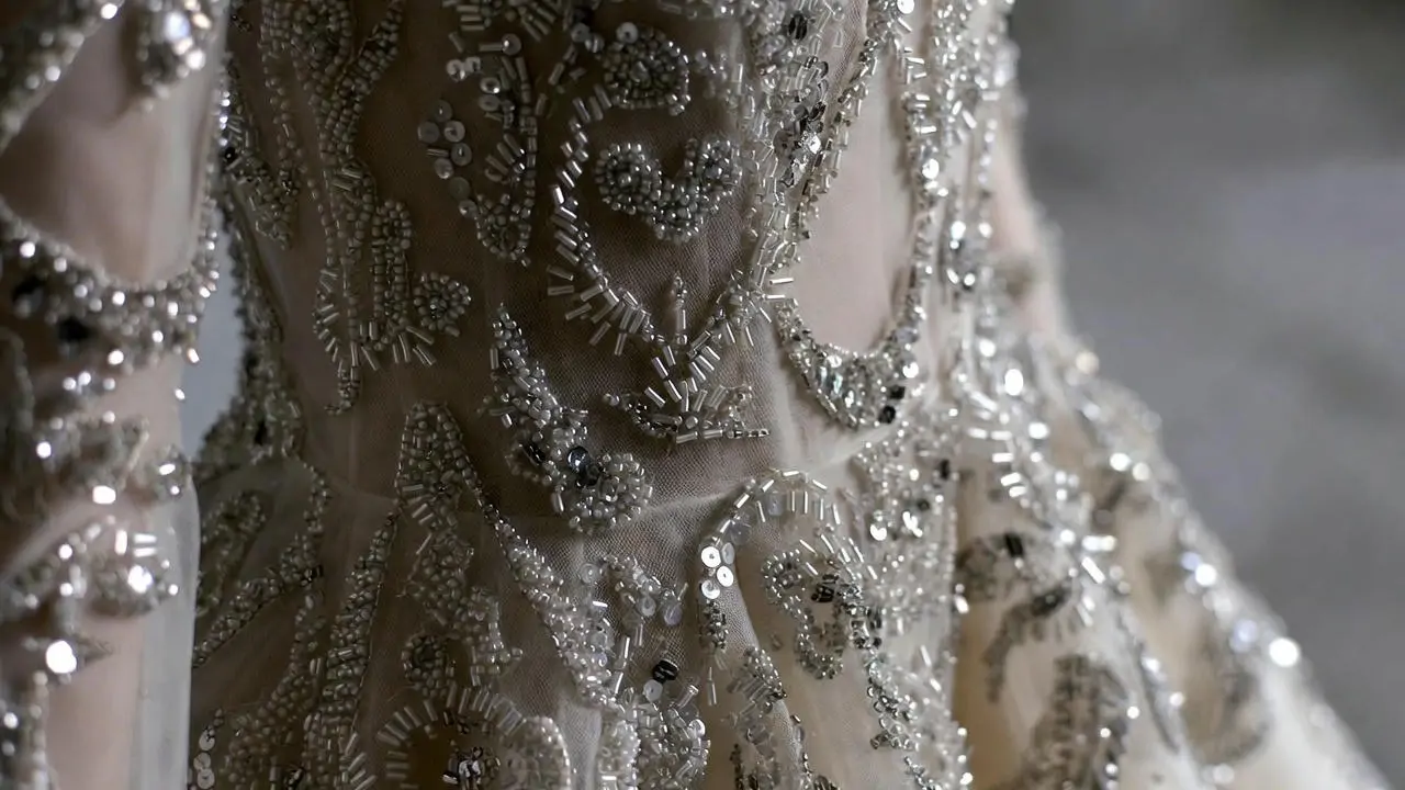 Elegant fashion detail close-up showing intricate hand-embroidery and beadwork on a haute couture gown